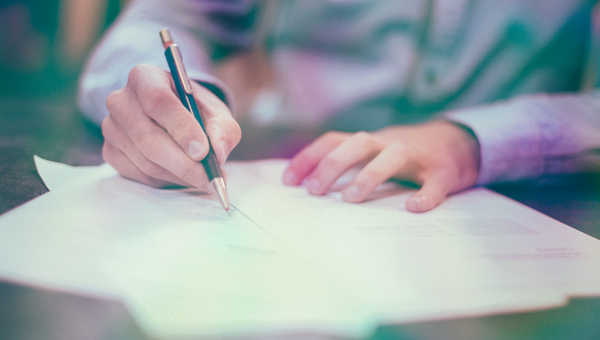 Person, die Papierdokumente ausfüllt